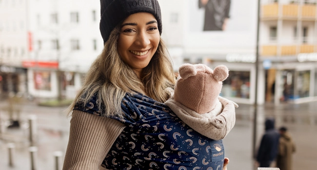 Mutter trägt baby in der manduca babytrage und geht in der Stadt