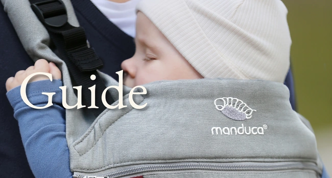 Baby schläft in der manduca Babytrage es steht die aufschrift Guide nebendrann