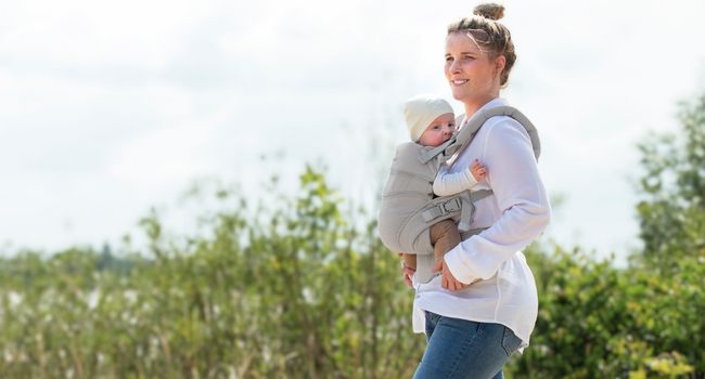 Mutter trägt baby in der manduca babytrage und läuft in der natur